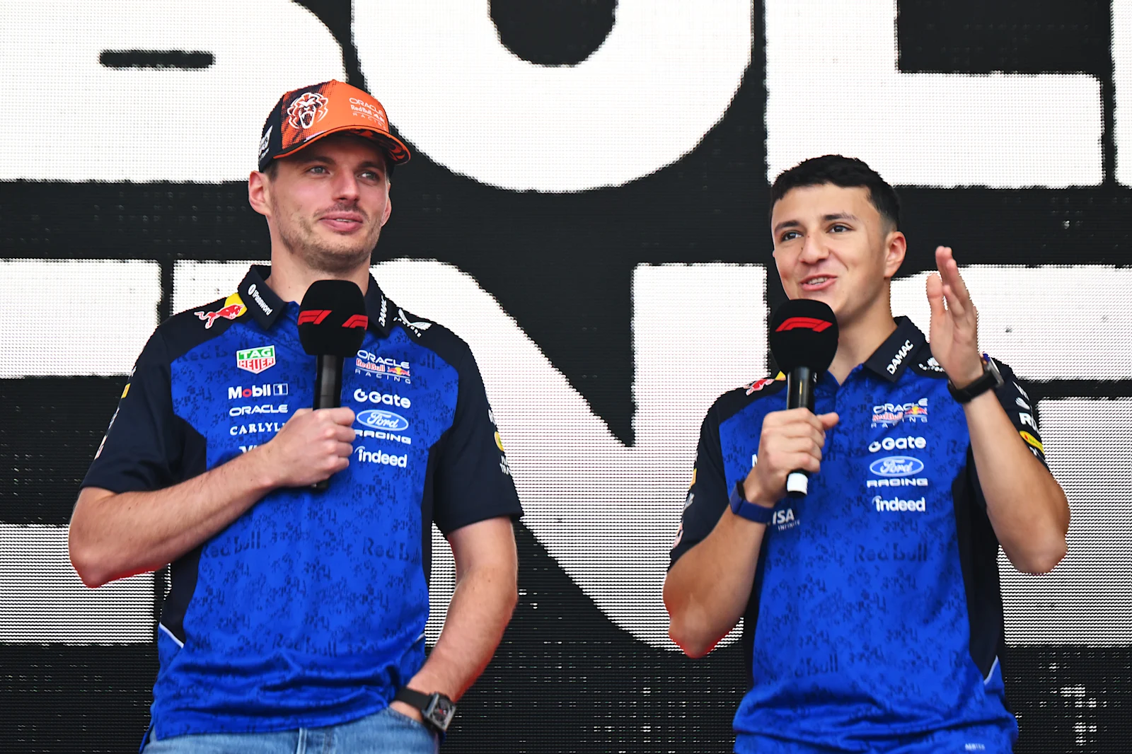 Max Verstappen ile Isack Hadjar takım etkinliğinde mikrofonla konuşurken