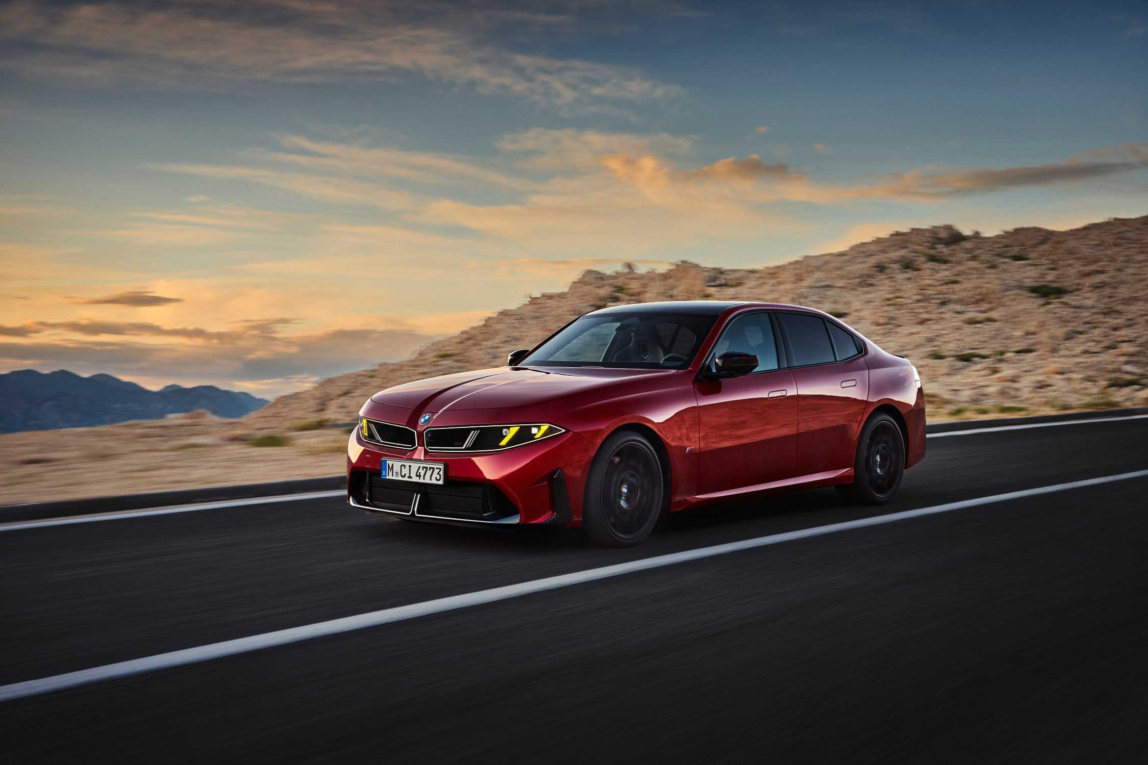BMW 3 Serisi gamının tepesindeki M350 xDrive kırmızı gövde rengiyle kayalık yamacın önünde hareket halinde