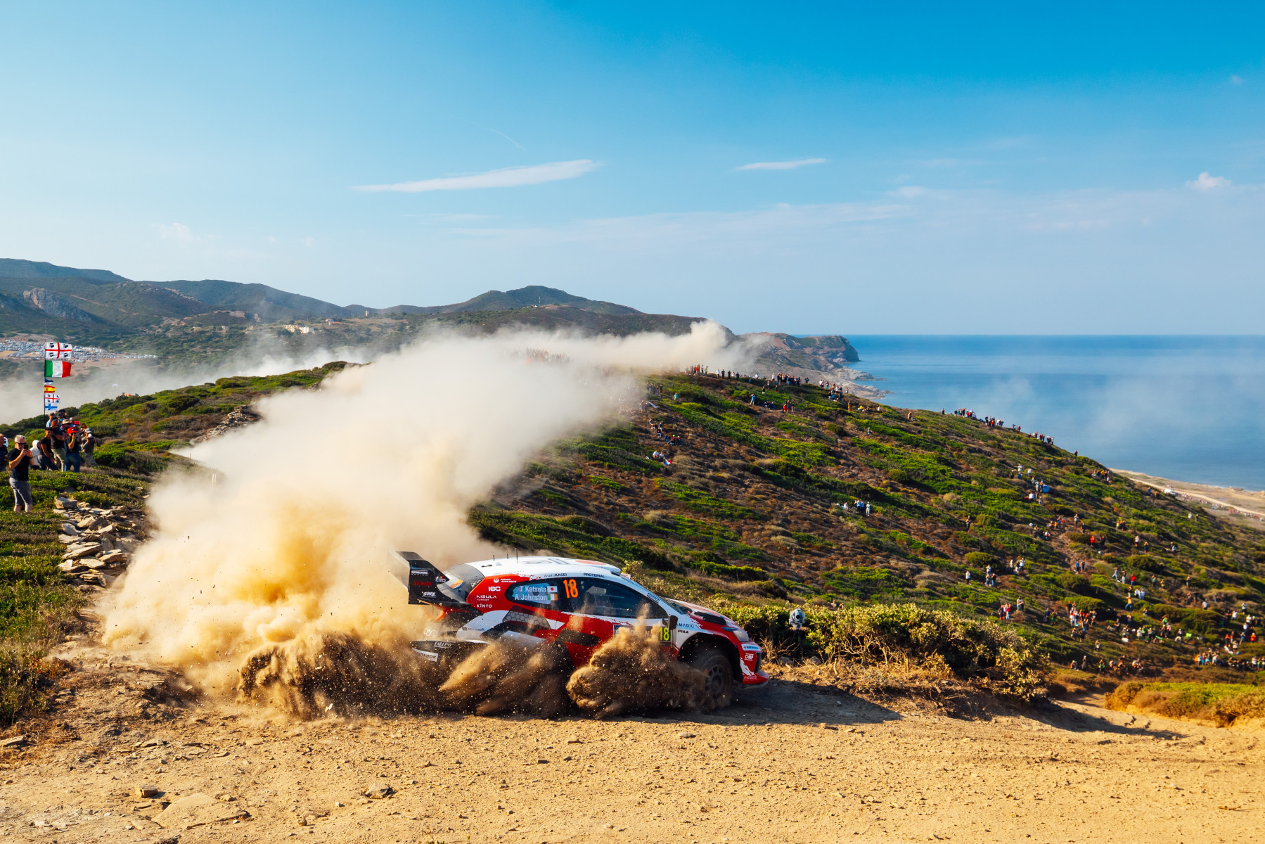 Takamoto Katsuta'nın 18 numaralı GR Yaris Rally1 modeli, Sardinya kıyısındaki çakıl etabında toz kaldırırken