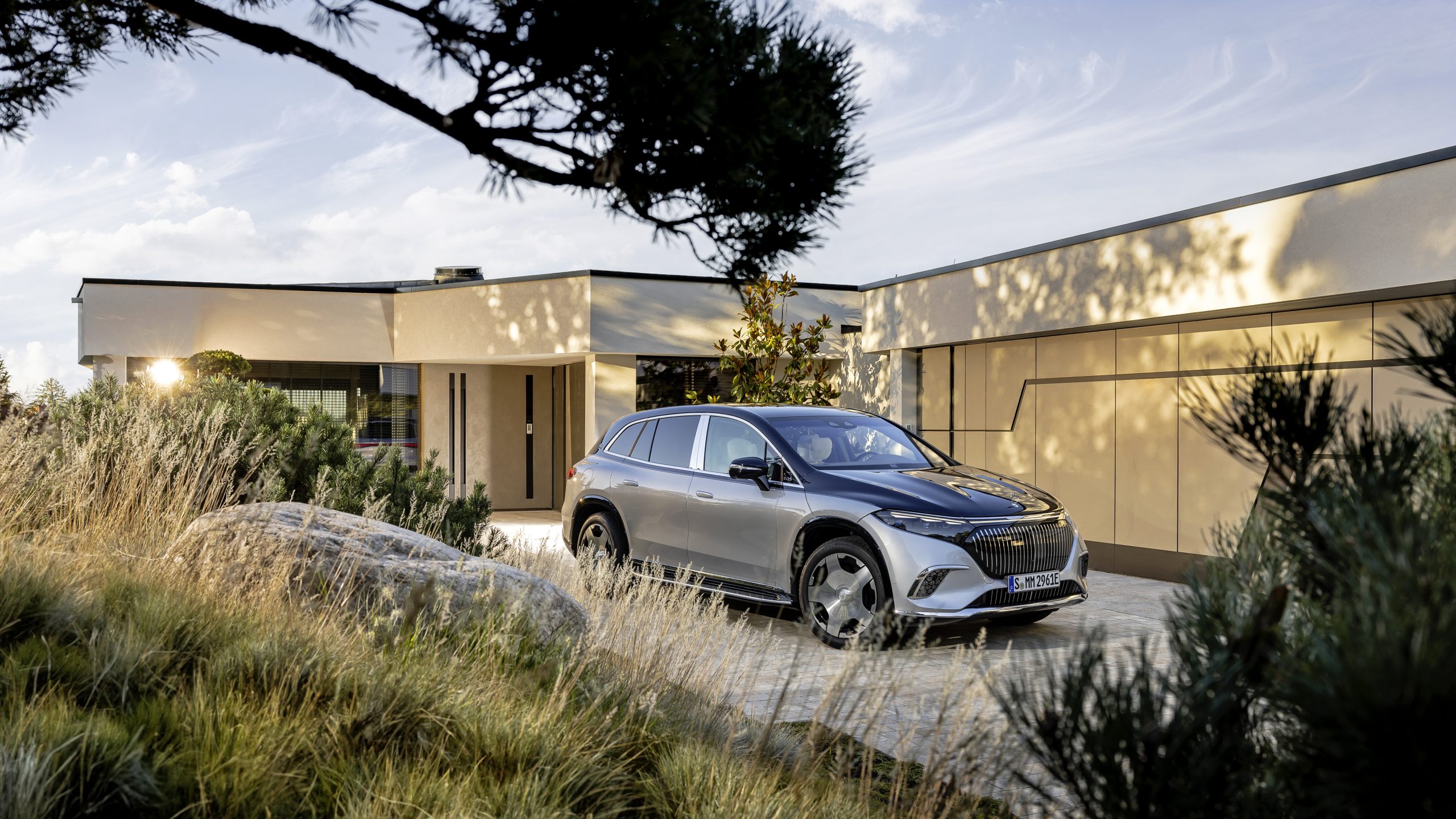 İki renkli gövdeye sahip Mercedes-Maybach EQS 680 SUV bir ev girişinde duruyor