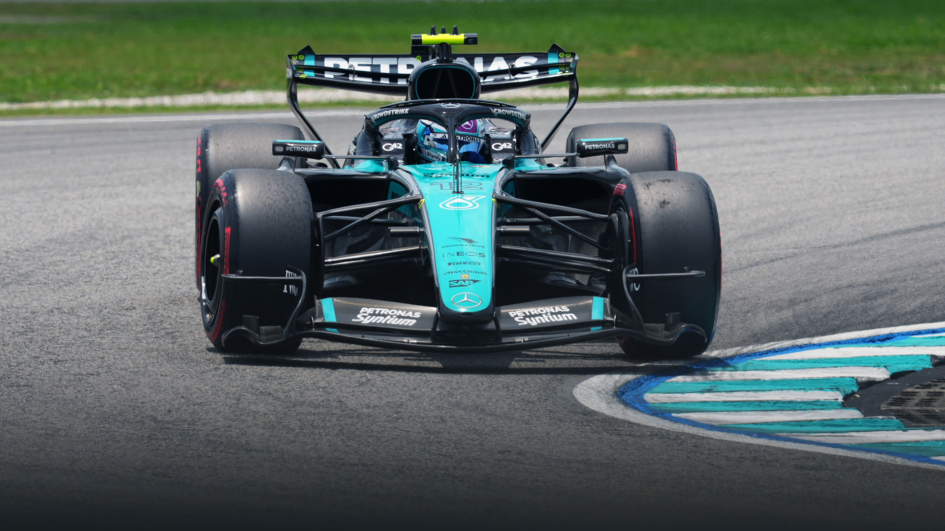 12 numaralı Mercedes W17 Sepang'da yumuşak lastiklerle viraj çıkışında kerb üzerinden geçerken