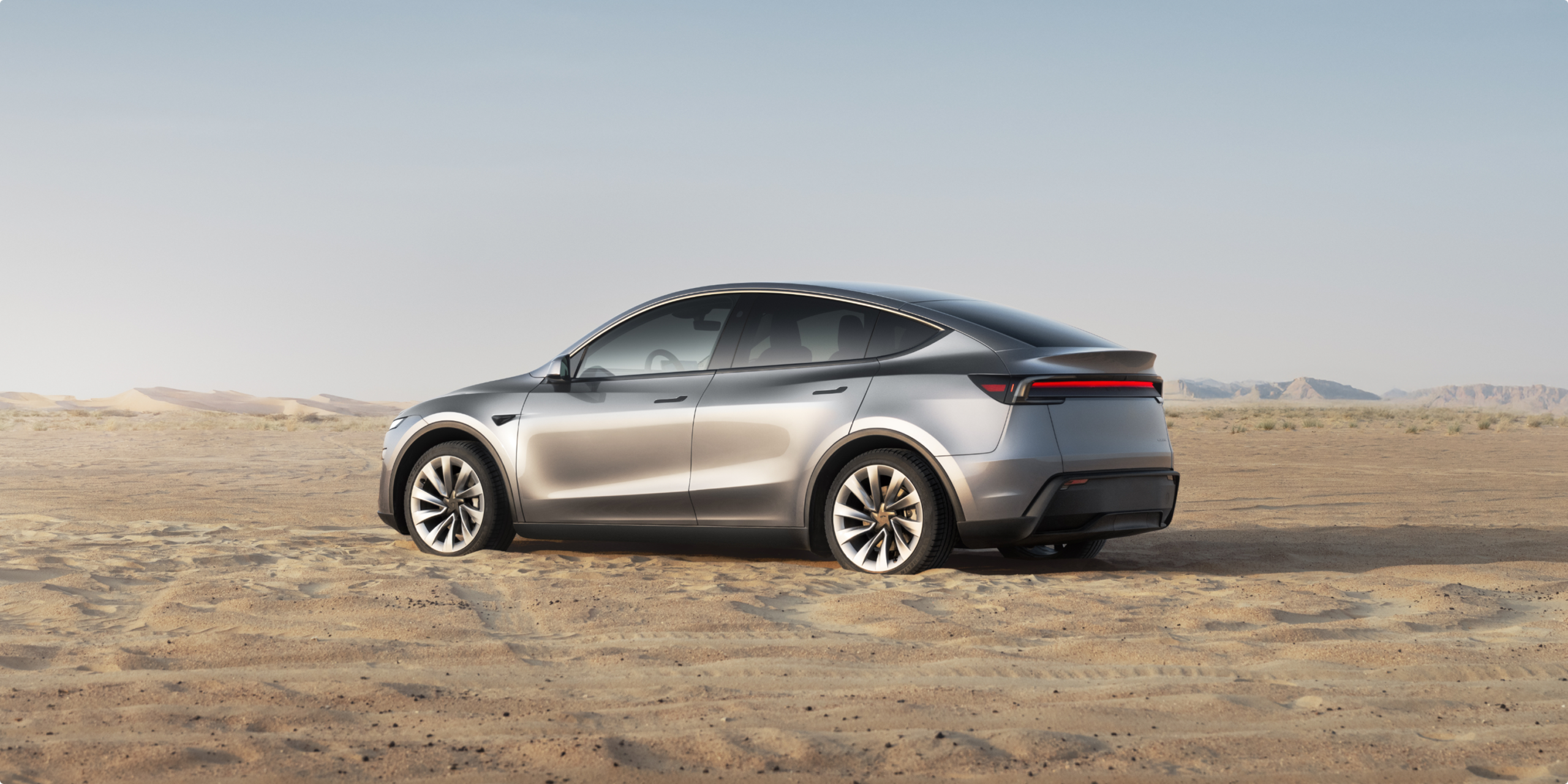 Tesla Model Y fiyat listesinde zamdan etkilenmeyen gri gövdeli sürümün arkadan üç çeyrek görünümü