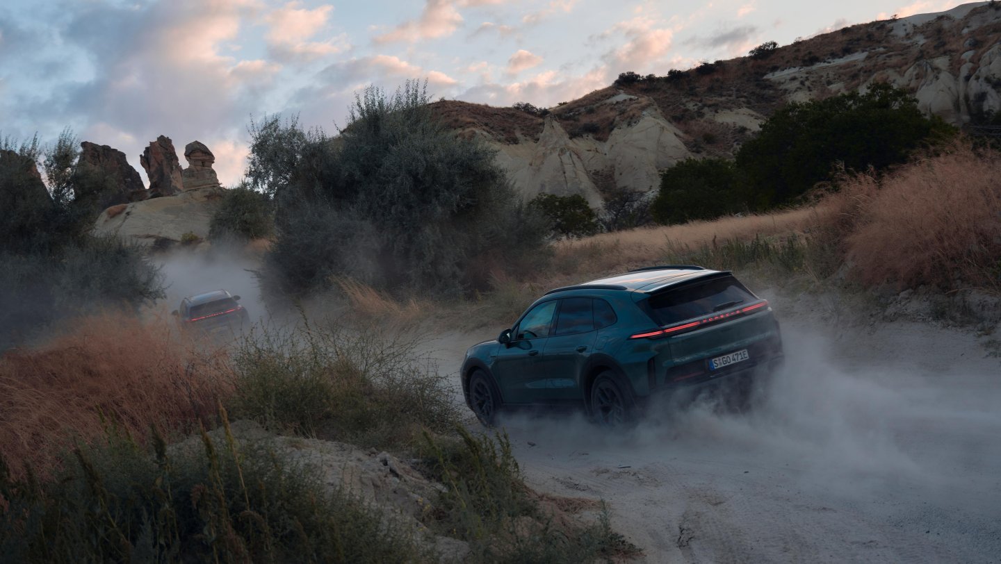 Kapadokya'da kayalıklar arasındaki asfalt yolda giden Cayenne Electric
