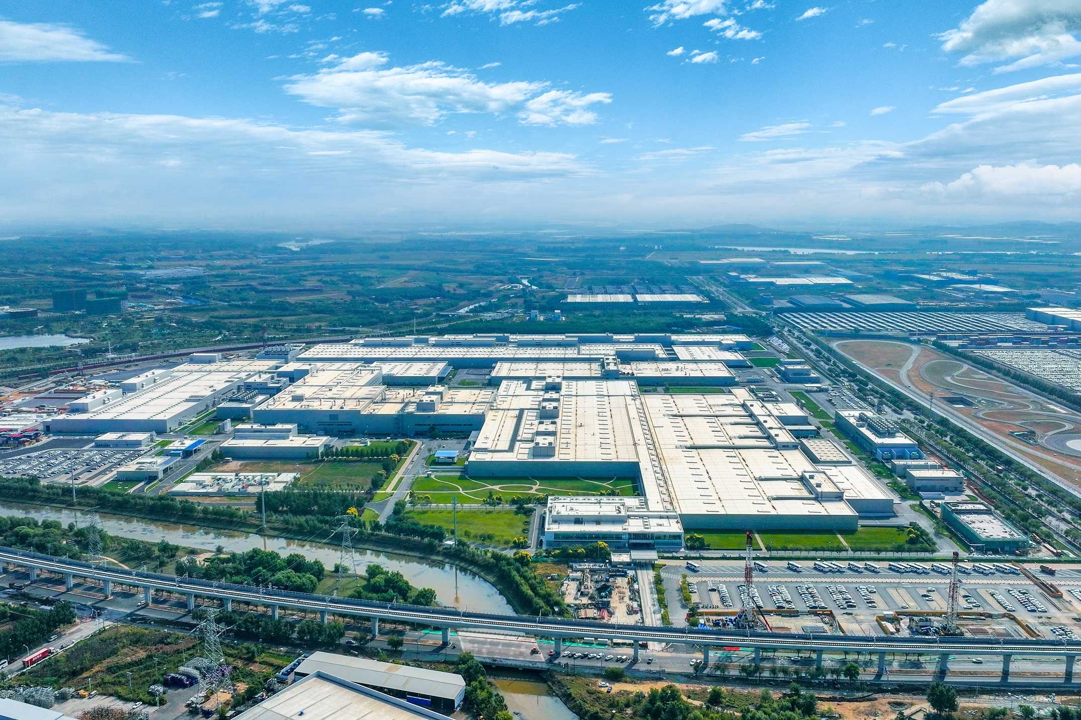 BMW Shenyang motor ve yüksek voltaj batarya fabrikasının hava görüntüsünde geniş çatılı üretim binaları, çevresindeki yollar ve yeşil alanlar görülüyor