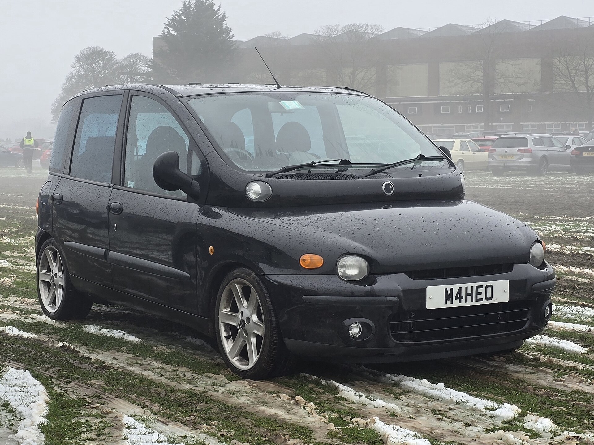 Karla kaplı zeminde duran siyah Fiat Multipla otomobilinin önden görünümü