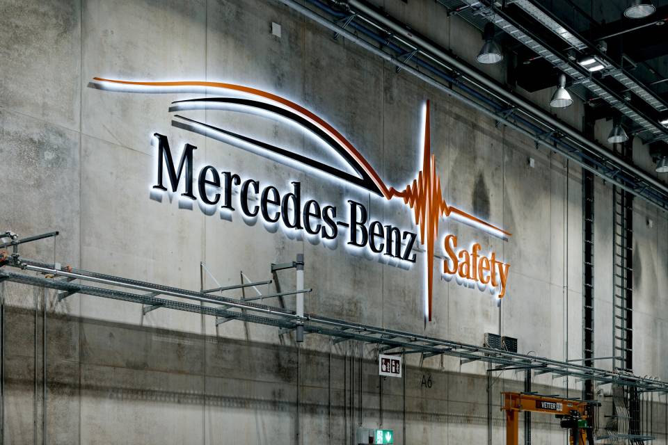 Mercedes-Benz Safety yazısı ve ışıklı logosu çarpışma testi tesisinin beton duvarında görünüyor