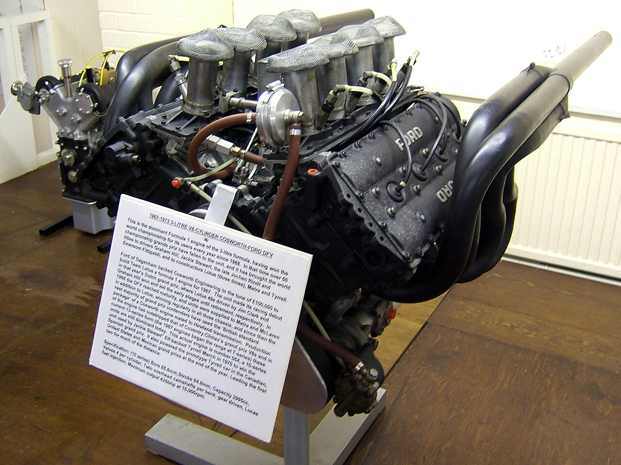 Müzede sergilenen Cosworth DFV V8 Formula 1 motoru ve yanındaki bilgi levhası