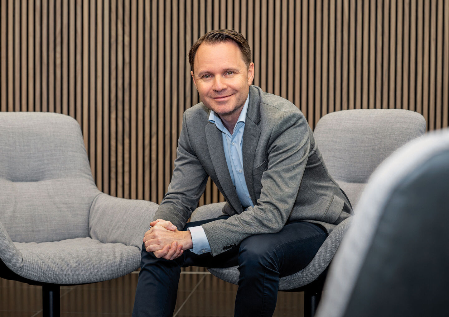 Rolf Michl, Audi China bünyesinde işletme direktörü olarak çalışacak yöneticinin oturur vaziyette gülümsediği bir ofis fotoğrafında gri ceketle görülüyor