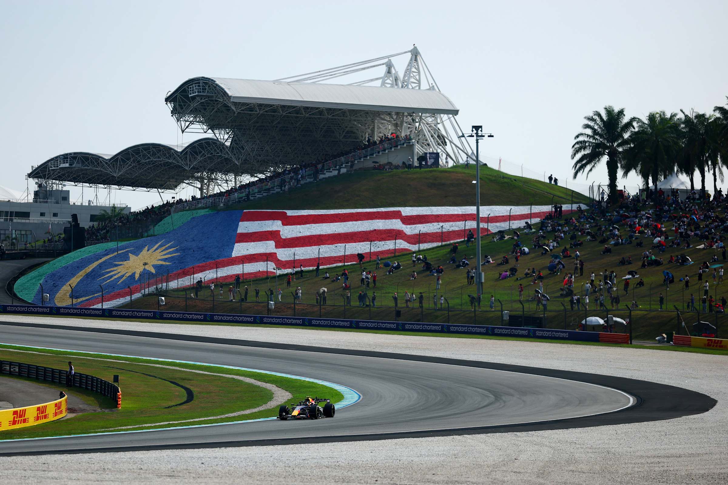 Sepang ana tribünü ve Malezya bayrakları, virajda ilerleyen bir Red Bull