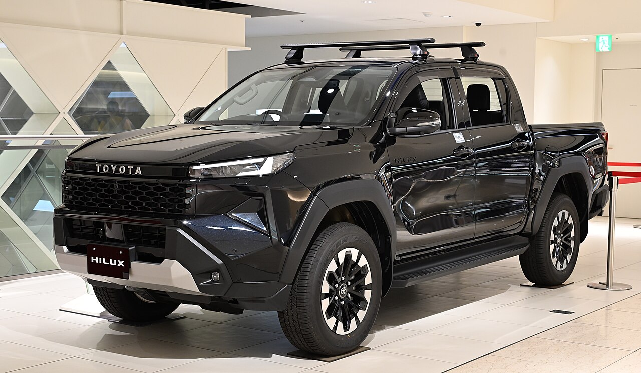 Toyota Hilux çift kabin kamyonet, tavan barlı siyah gövdesiyle showroom ortamında sergileniyor