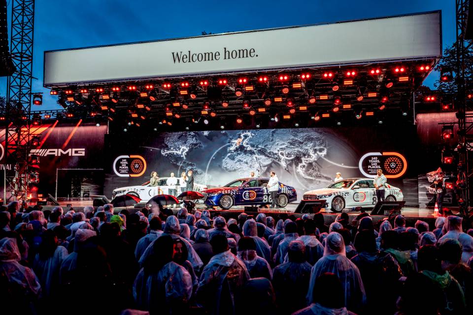 Üzerinde Welcome home yazan sahnede sıralanan üç Mercedes-Benz S-Serisi limuzini ve izleyiciler