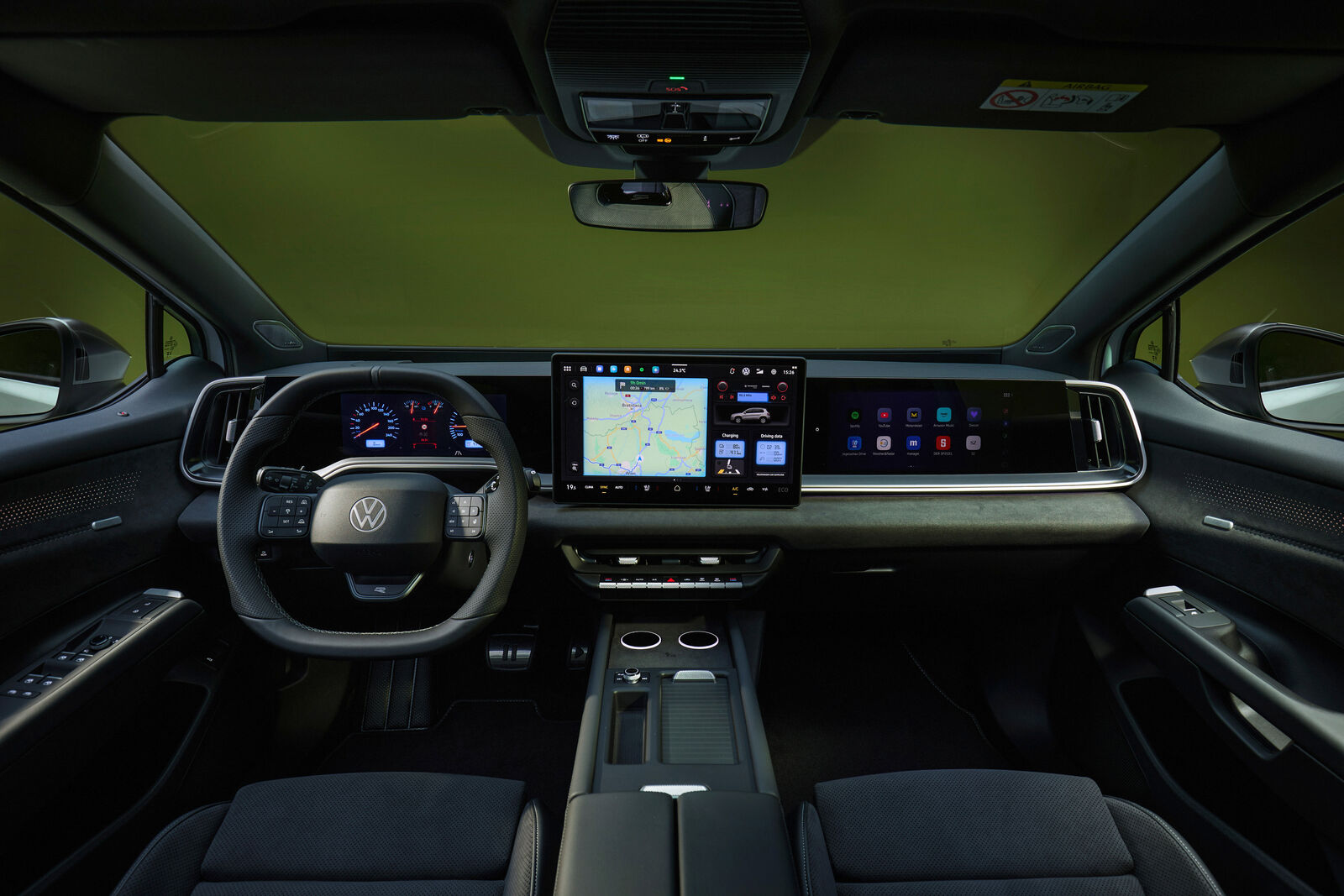 Volkswagen ID. Tiguan kabininde geniş ekran düzeni, direksiyon simidi ve orta konsol, koyu renk döşeme ve yeşil tonlu iç mekân aydınlatmasıyla görülüyor